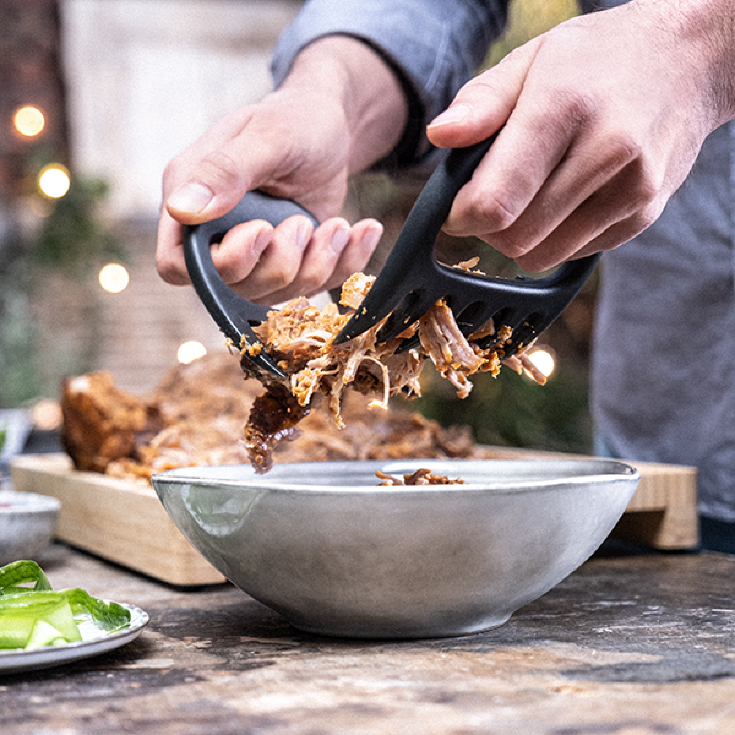 BBQ meat claws held in hands, dark charcoal grips with pointed tines