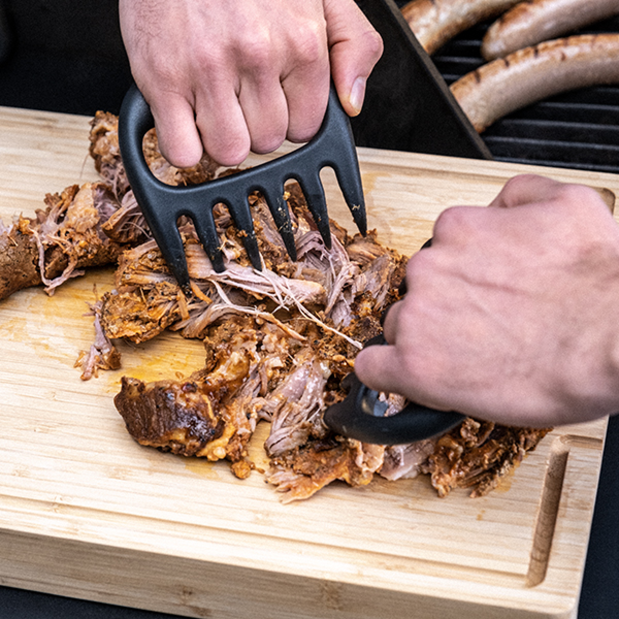 BBQ meat claws pressed into shredded meat, dark charcoal handle with tines