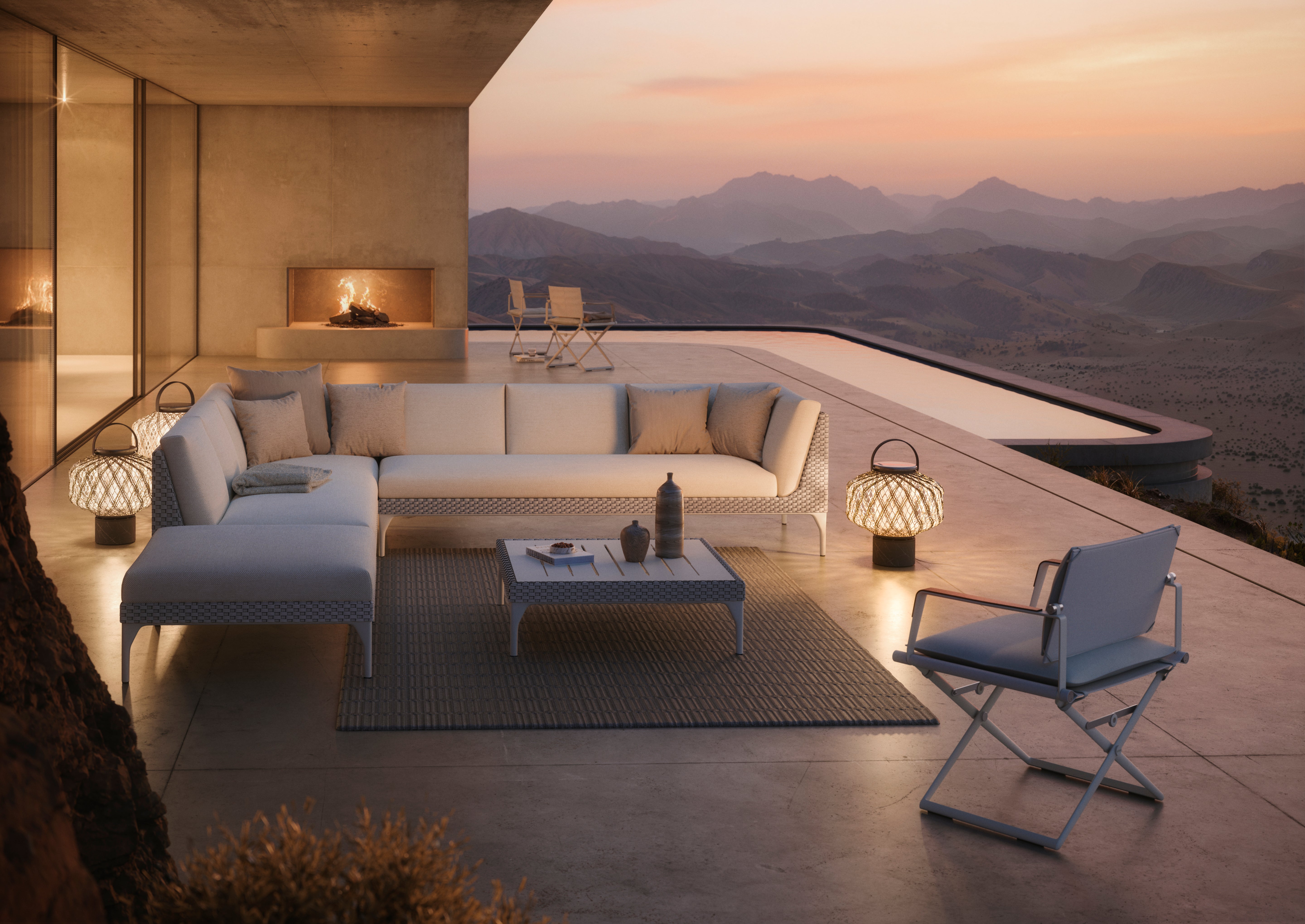 Mu by Dedon outdoor lounge collection with woven seating and lanterns on a hillside terrace at dusk