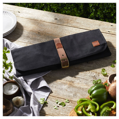 Black fabric grill tool roll with brown leather strap on tabletop