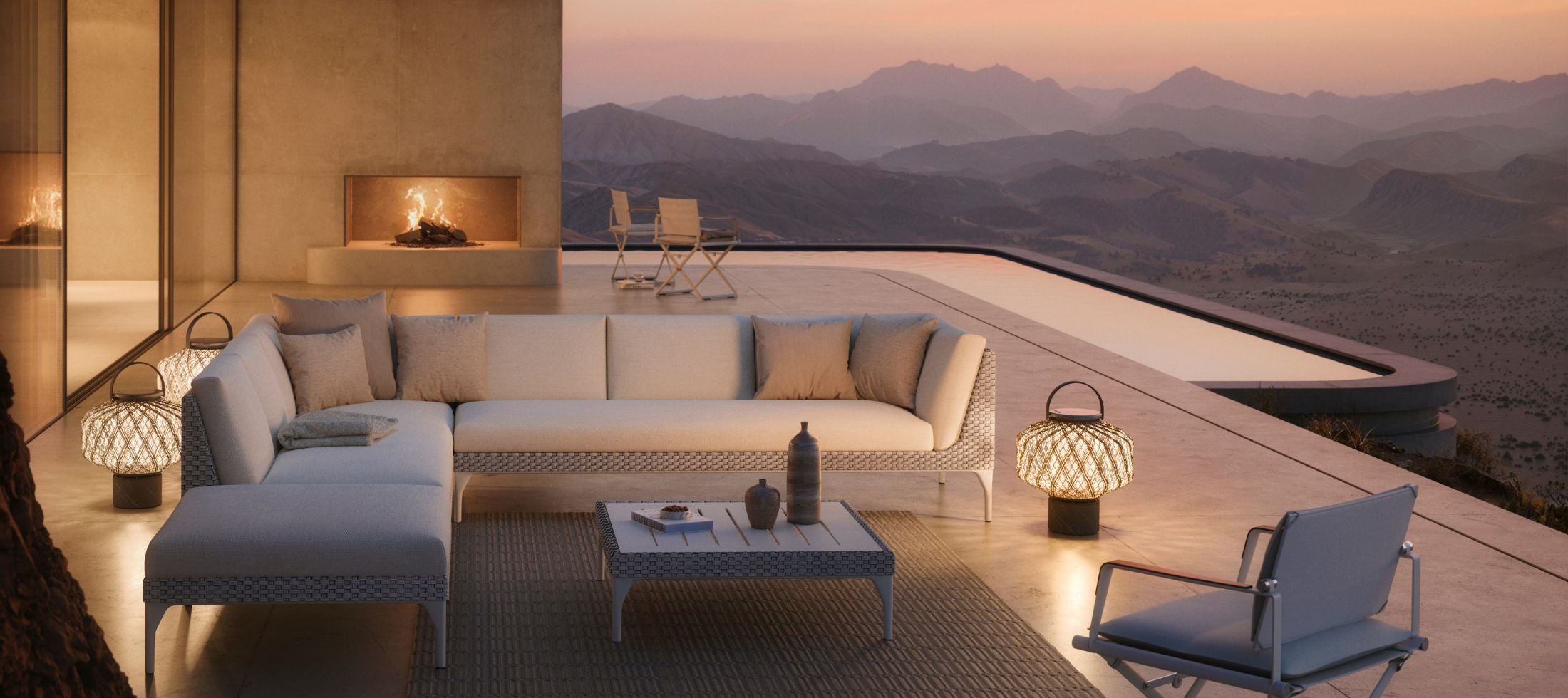 Mu by Dedon outdoor lounge collection with woven seating and lanterns on a hillside terrace at dusk